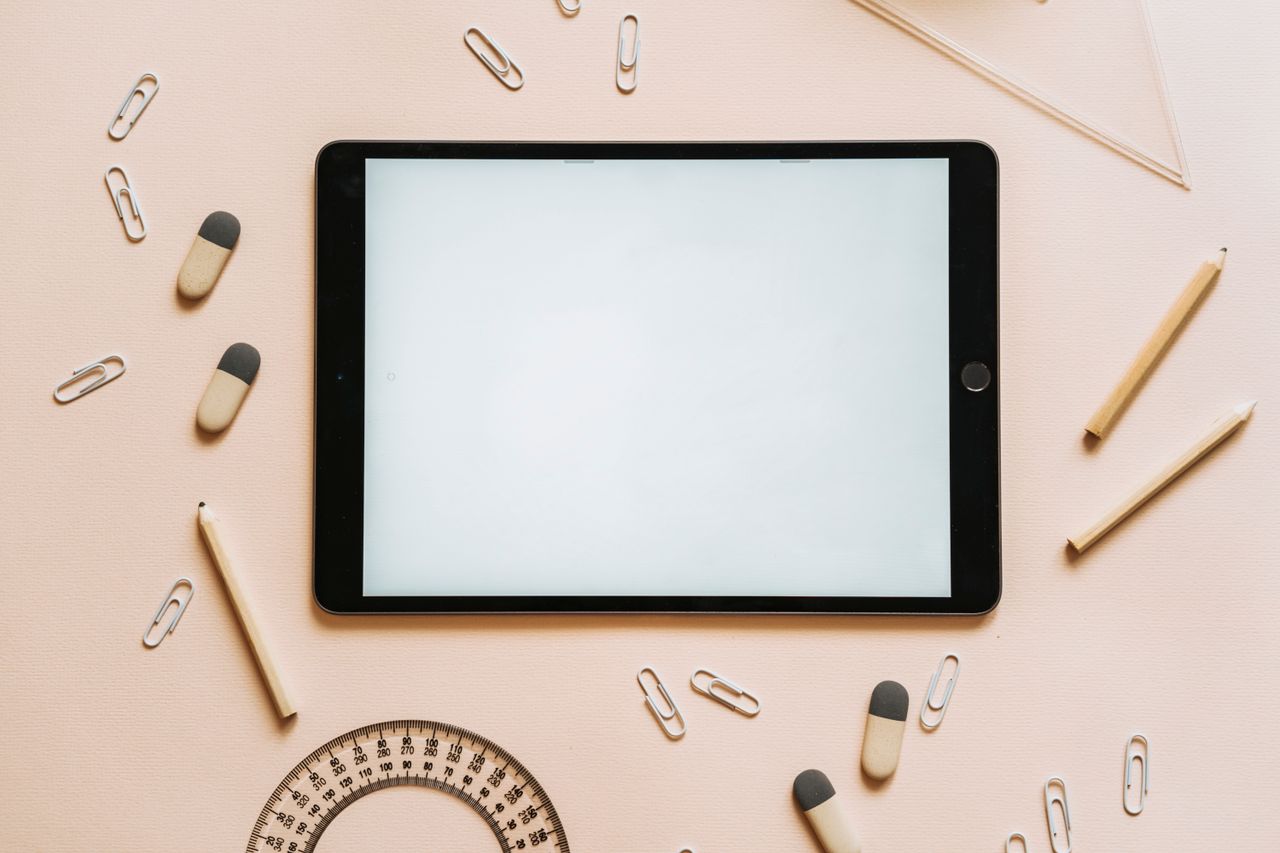 The Art of Drawing Readers In: Your attractive post title goes here A tablet surrounded by stationery items like pencils, erasers, and paper clips in a flat lay setup.