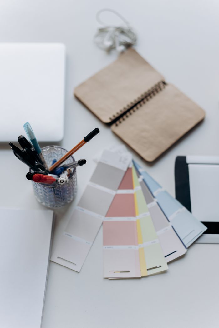 Offerings Organized workspace featuring color swatches, notebook, laptop, and stationery for design projects.