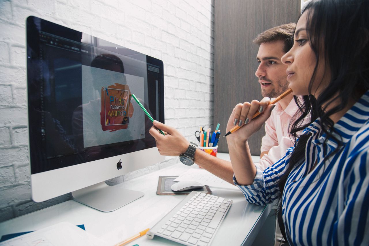 Mastering the First Impression: Your intriguing post title goes here Side view of focused coworkers working together on graphic design while sitting at table and looking at monitor in modern office