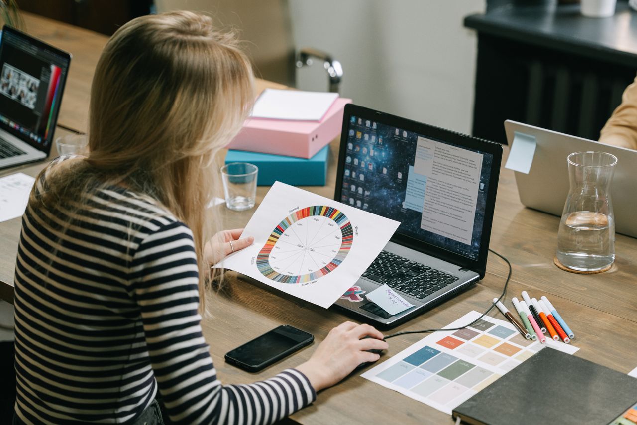 Offerings A woman studying a color wheel on a laptop during a work session in a modern office.